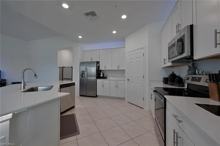 Kitchen with stainless steel appliances, finishes, recessed lighting, white cabinets, light tile patterned floors, and light stone countertops