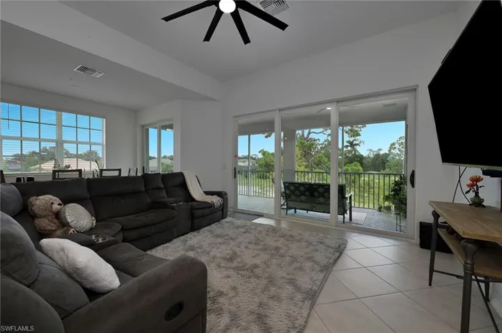 Living area with light tile patterned flooring, plenty of natural light, ceiling fan and views!