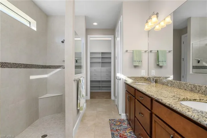 Bathroom featuring vanity, a tile shower, and tile patterned floors