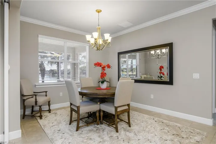 Dining space with crown molding, tile patterned floors, and a chandelier