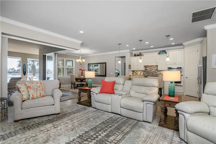 Living room with crown molding, an inviting chandelier, and light tile patterned floors