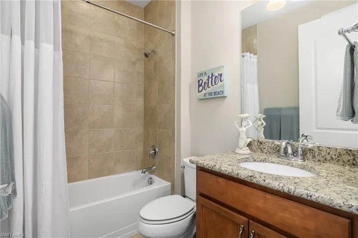 Full bathroom with vanity, shower / bathtub combination with curtain, and toilet
