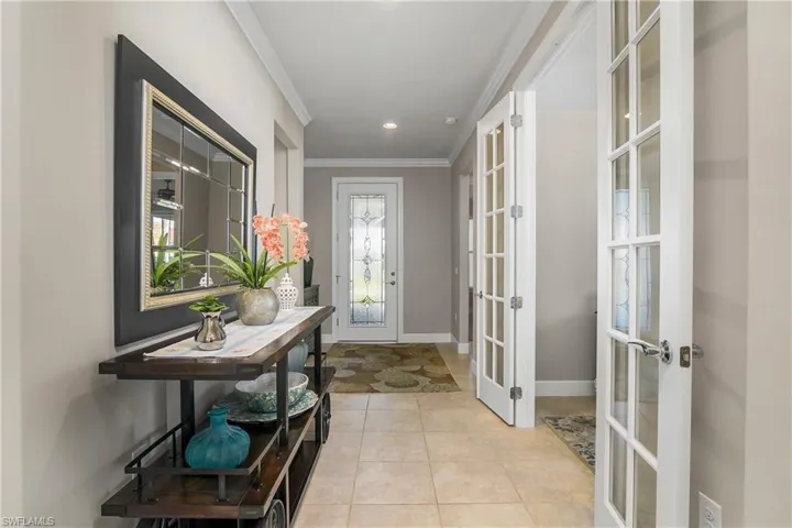 Doorway to outside featuring ornamental molding, light tile patterned flooring, and french doors