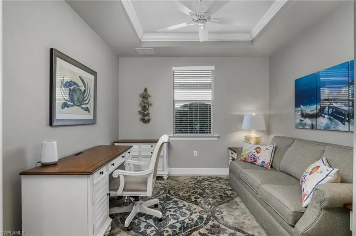 Home office featuring a tray ceiling, ornamental molding, and ceiling fan