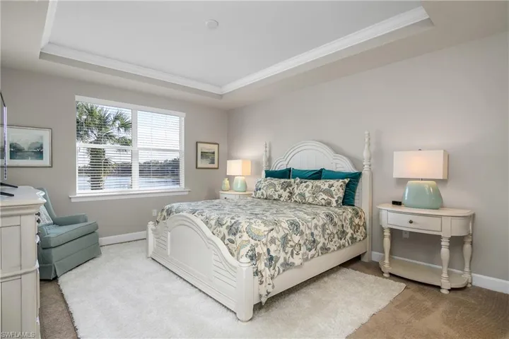 Bedroom with light carpet, crown molding, and a raised ceiling