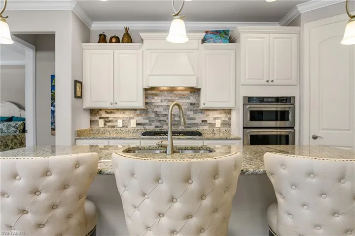 Kitchen with double oven, decorative light fixtures, and light stone countertops