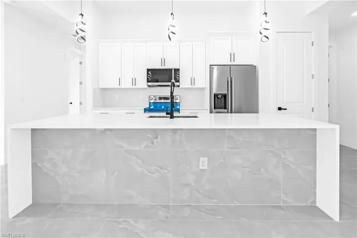 Kitchen island featuring a white countertop and large format tile facing