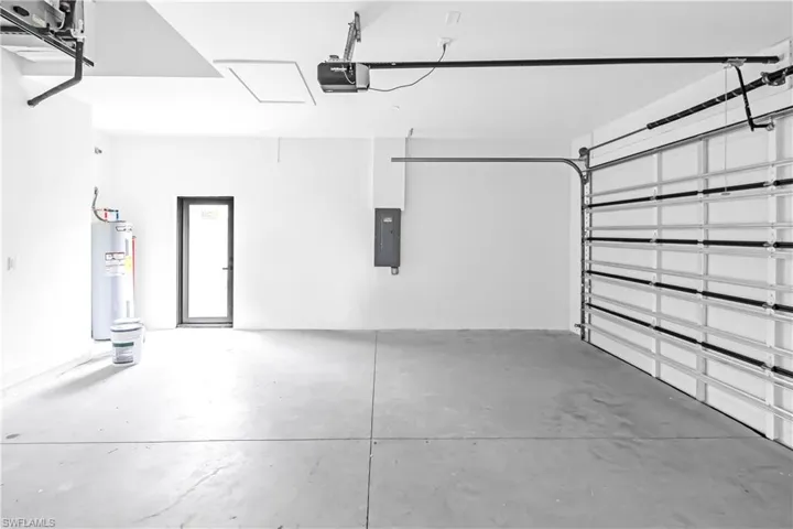 Spacious garage with a concrete floor, overhead door, and dedicated utility access