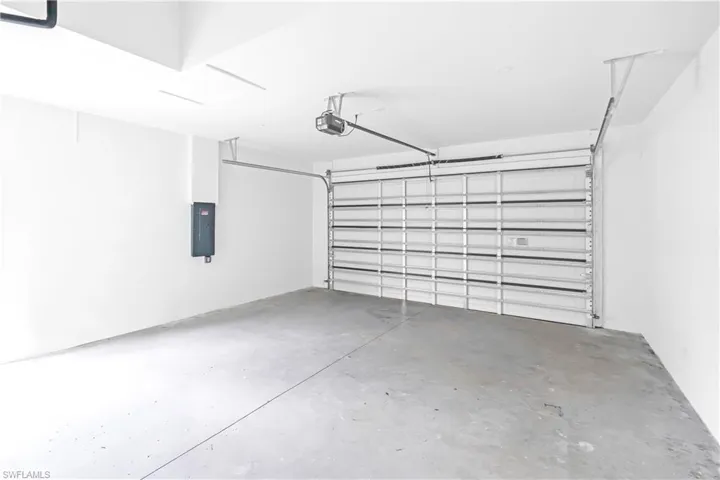 Spacious garage featuring a concrete floor, white walls, and an overhead door opener mechanism