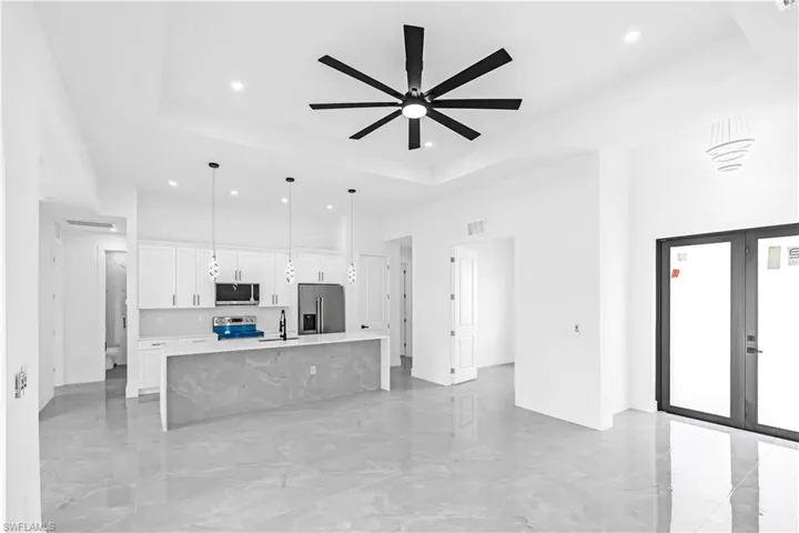 Open-concept living space featuring light gray tile flooring and a tray ceiling with a contemporary ceiling fan