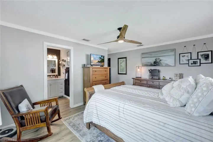Bedroom featuring sink, connected bathroom, ornamental molding, ceiling fan, and light wood-style vinyl flooring