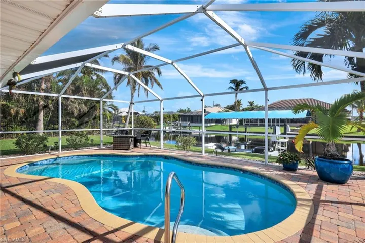 View of swimming pool with a water view, glass enclosure, and a patio area