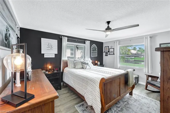 Bedroom featuring ceiling fan, multiple windows, and light wood-style vinyl flooring
