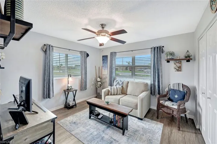 Living room featuring light wood-style vinyl flooring, a textured ceiling, and plenty of natural light