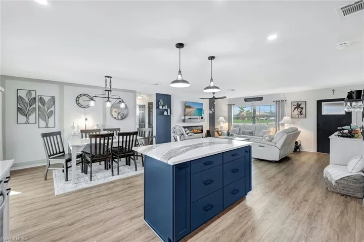 Kitchen featuring light stone counters, a kitchen island, light wood-style vinyl flooring, decorative light fixtures, and blue cabinets