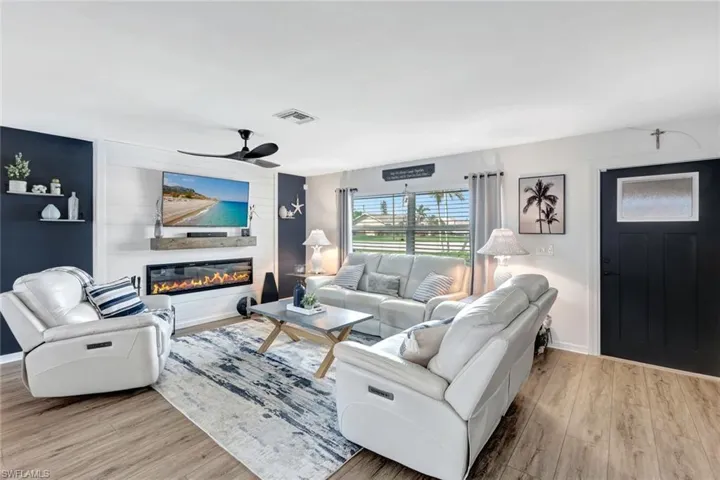 Living room with a fireplace, light wood-style vinyl floors, and ceiling fan