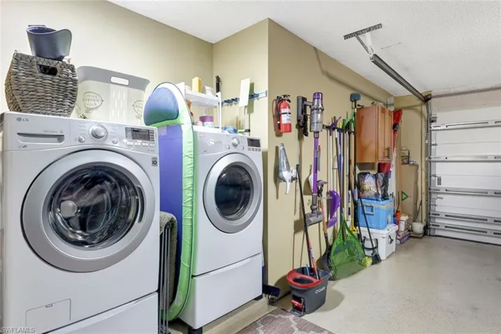 Clothes washing area featuring washer and clothes dryer and a textured ceiling