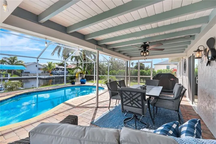 View of swimming pool featuring glass enclosure, a patio area, a water view, and ceiling fan