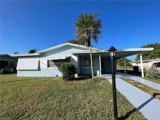 View of front of home with a carport and a front lawn