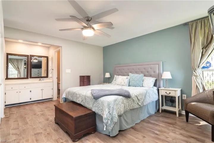 Bedroom with ceiling fan, light hardwood / wood-style flooring, and ensuite bath