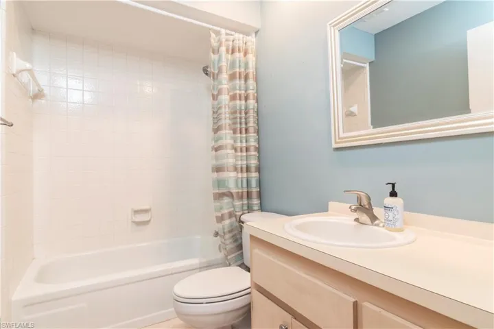 Full bathroom featuring shower / tub combo with curtain, oversized vanity, and toilet