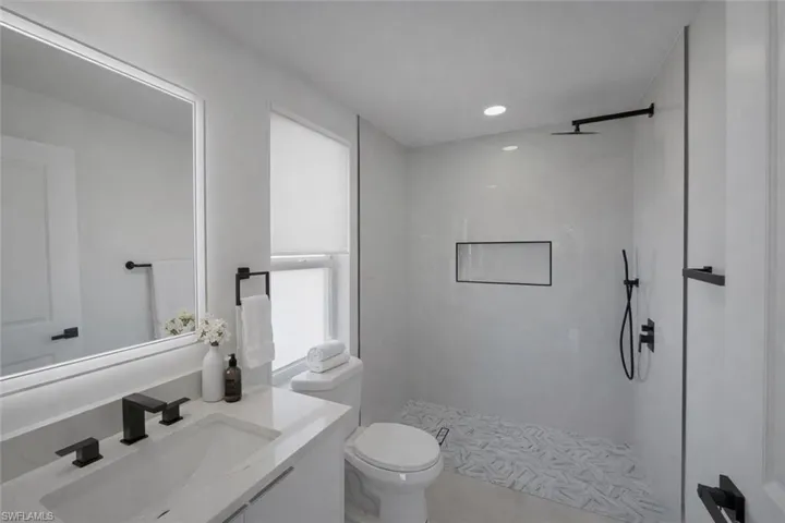 Full bathroom with vanity, walk in shower, recessed lighting, and light tile patterned floors