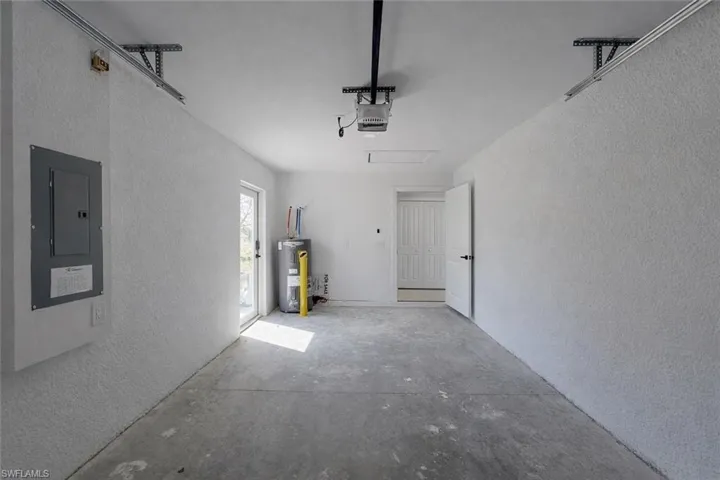 4529_Garage with a textured wall, electric panel, and electric water heater