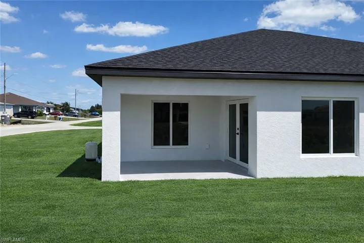 4531_Rear view of house featuring a yard, roof with shingles, stucco siding, and a patio area