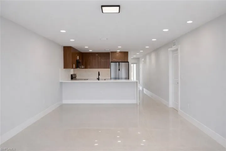Kitchen featuring a peninsula, recessed lighting, stainless steel fridge, modern cabinets, and tasteful backsplash