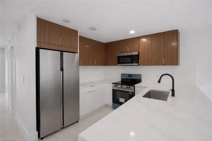 Kitchen with stainless steel appliances, light stone countertops, modern cabinets, recessed lighting, and tasteful backsplash