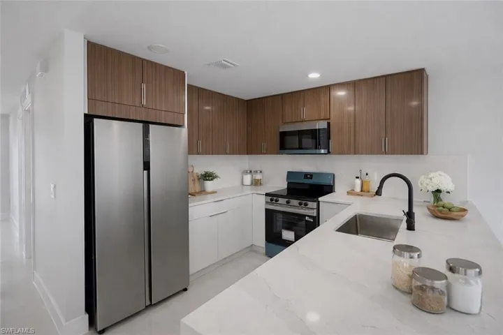 Kitchen with stainless steel appliances, light stone counters, modern cabinets, recessed lighting, and backsplash