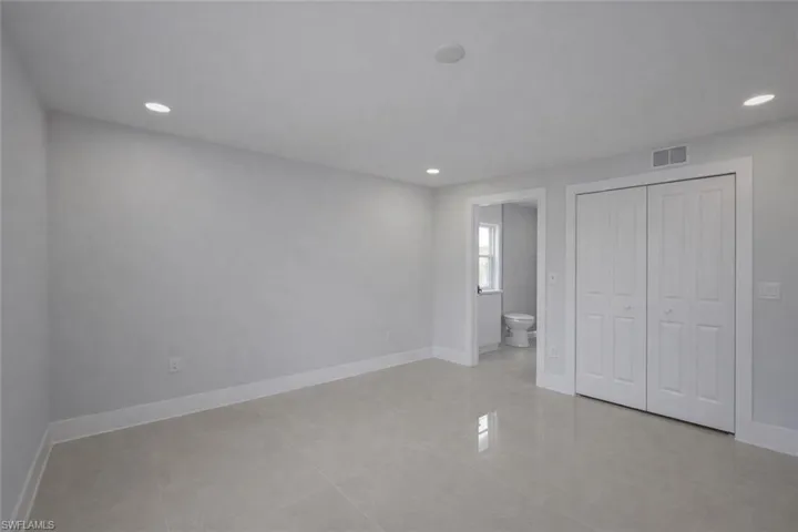 Unfurnished bedroom with a closet, recessed lighting, ensuite bathroom, and light tile patterned flooring