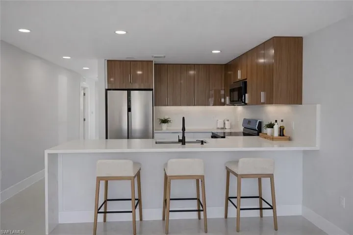 Kitchen with a peninsula, stainless steel appliances, light stone counters, modern cabinets, and recessed lighting