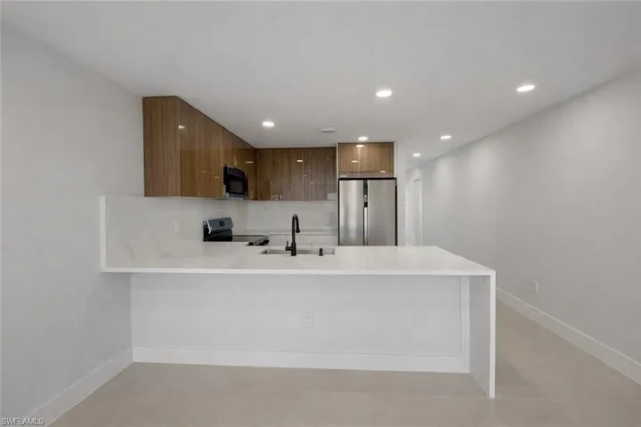 4529_Kitchen with a peninsula, freestanding refrigerator, light stone countertops, recessed lighting, and modern cabinets