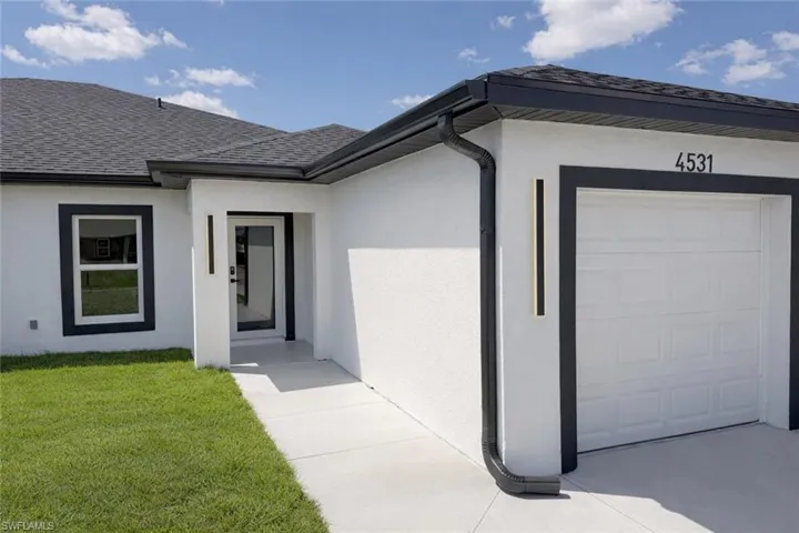 Entrance to property with a garage, stucco siding, and a yard