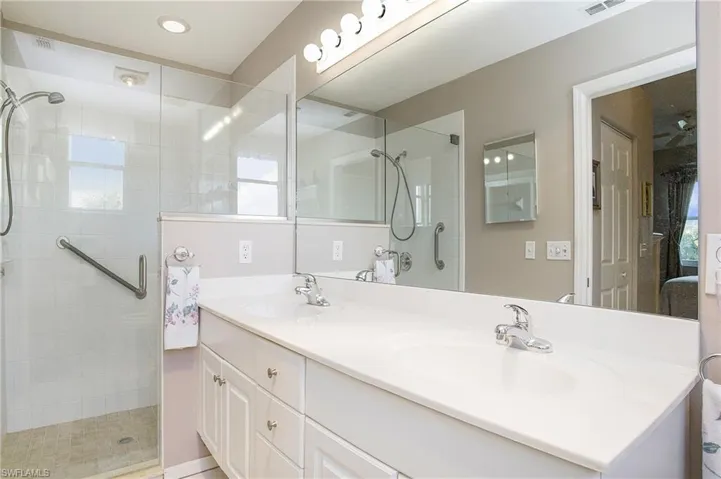 Primary Bedroom featuring a shower with door and vanity