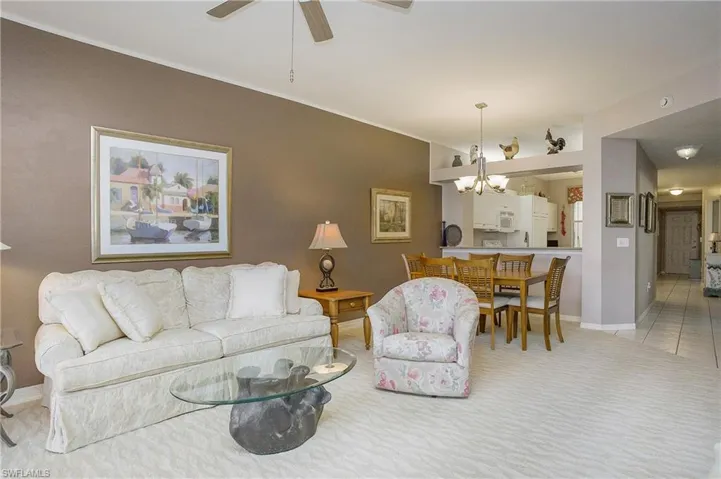 Tiled living room with ceiling fan with notable chandelier