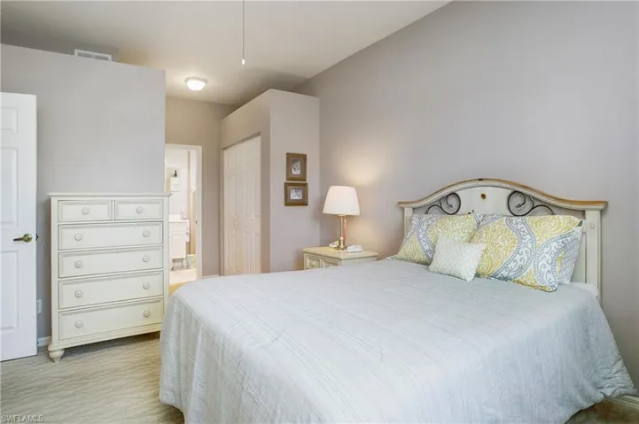 Primary Bedroom with ensuite bathroom, light colored carpet, and a closet