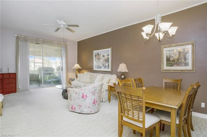Carpeted dining space with ceiling fan with notable chandelier