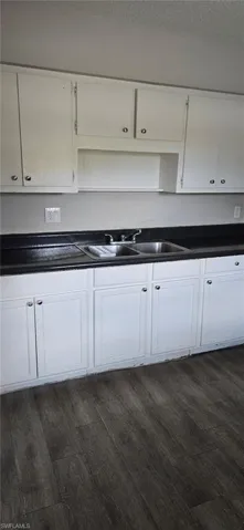 Kitchen with dark countertops, white cabinetry, and dark wood-style floors