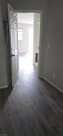 Corridor featuring baseboards and dark colored carpet