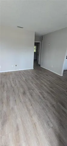 Empty room with wood finished floors and a textured ceiling