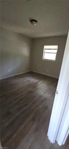 Spare room with dark wood-style flooring and a textured ceiling