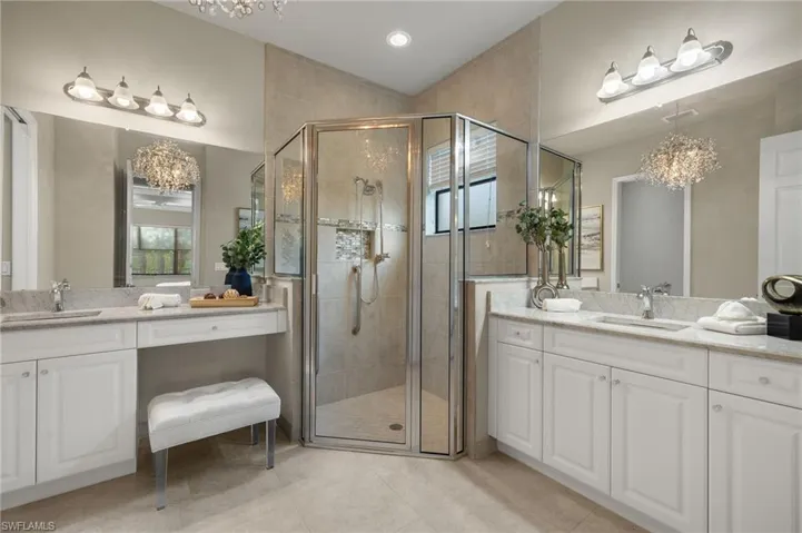 Bathroom featuring a chandelier, vanity, an enclosed shower, and tile patterned flooring