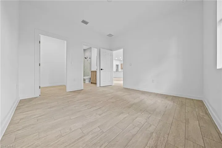Unfurnished bedroom with light wood-style floors and ensuite bathroom
