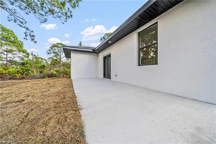View of side of property with stucco siding and a patio area