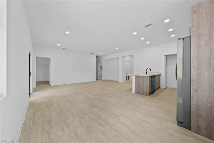 Unfurnished living room featuring a barn door, light wood-type flooring, and recessed lighting