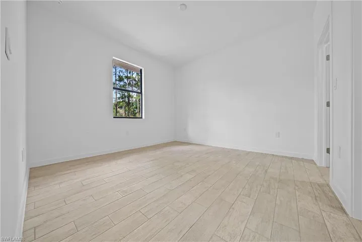 Spare room featuring light wood-type flooring and lofted ceiling