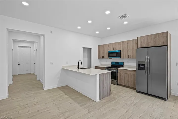 Kitchen featuring stainless steel appliances, a peninsula, modern cabinets, recessed lighting, and wood finish cabinets