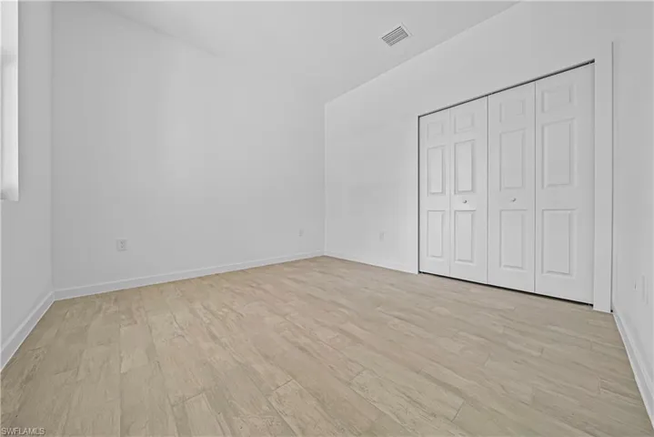 Unfurnished bedroom featuring light wood finished floors, a closet, and vaulted ceiling